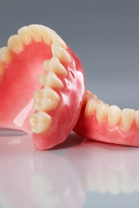 Complete set of dentures on a reflective off-white surface