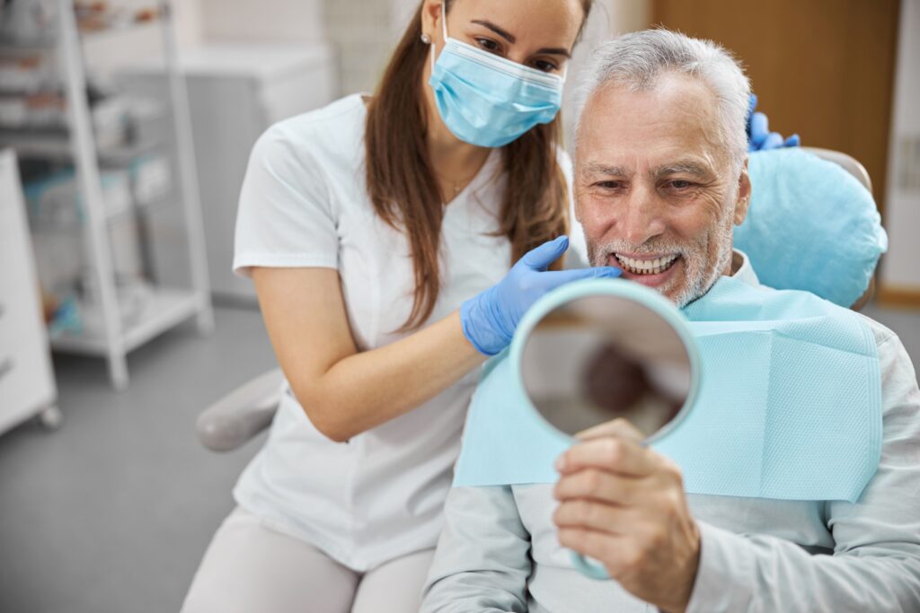 A dentist showing a patient his new dental implants with a hand mirror