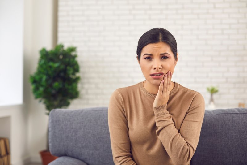 Patient holding their cheek due to tooth sensitivity