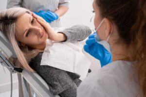 patient holding her face in pain with the dentist